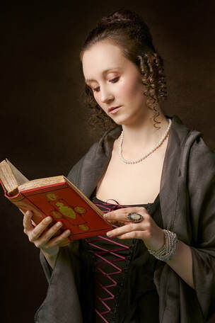 Woman from a previous era reading an old book.